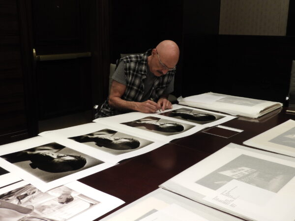 Tony Levin signing trial proofs of a vintage portrait he made Peter Gabriel, circa 1983