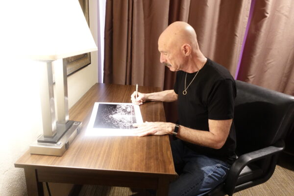 Tony Levin signing his print "Lay Your Hands on Me, 1983" featuring Peter Gabriel.