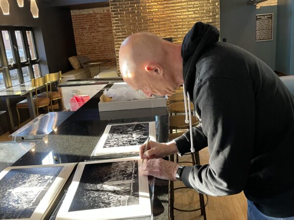 Tony Levin signing his print of Peter Gabriel, 2/23